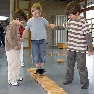 CUBITO-Baukasten-Bewegungsbaustelle: ein Junge rollt auf einem Brett über die Zylinder