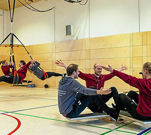 Sportstudenten an einer Bewegungsbaustelle mit Drehscheibe, Mehrzweckbrettern und Schaukel an der Schaukelkarussellplatte