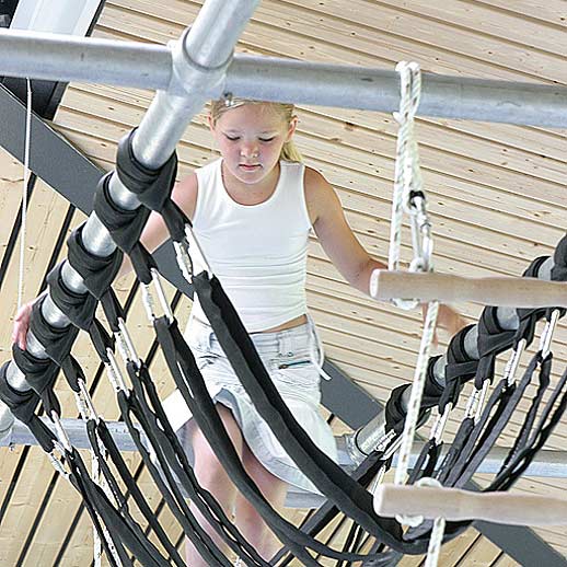 Ein Mädchen klettert auf der LOQUITO-Bewegungsbaustelle aus Endlosschlaufen, die am LOQUITO-Rohrsystem hängen.